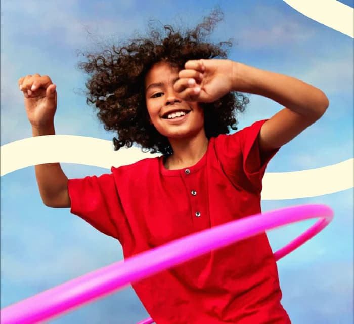 Niña con camiseta roja jugando con un hula-hoop rosa
